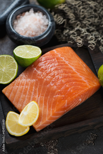 Close-up of raw salmon fillet with pink salt and limes, vertical shot, selective focus