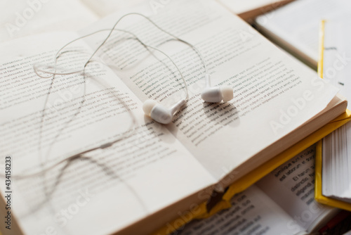 white earphones on stack of blurred books