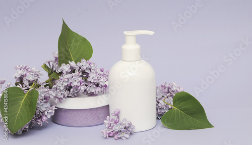 Group of cosmetic bottles with lilac on background.  Face scrub  gel shower and cream on violet background with lilac flowers.