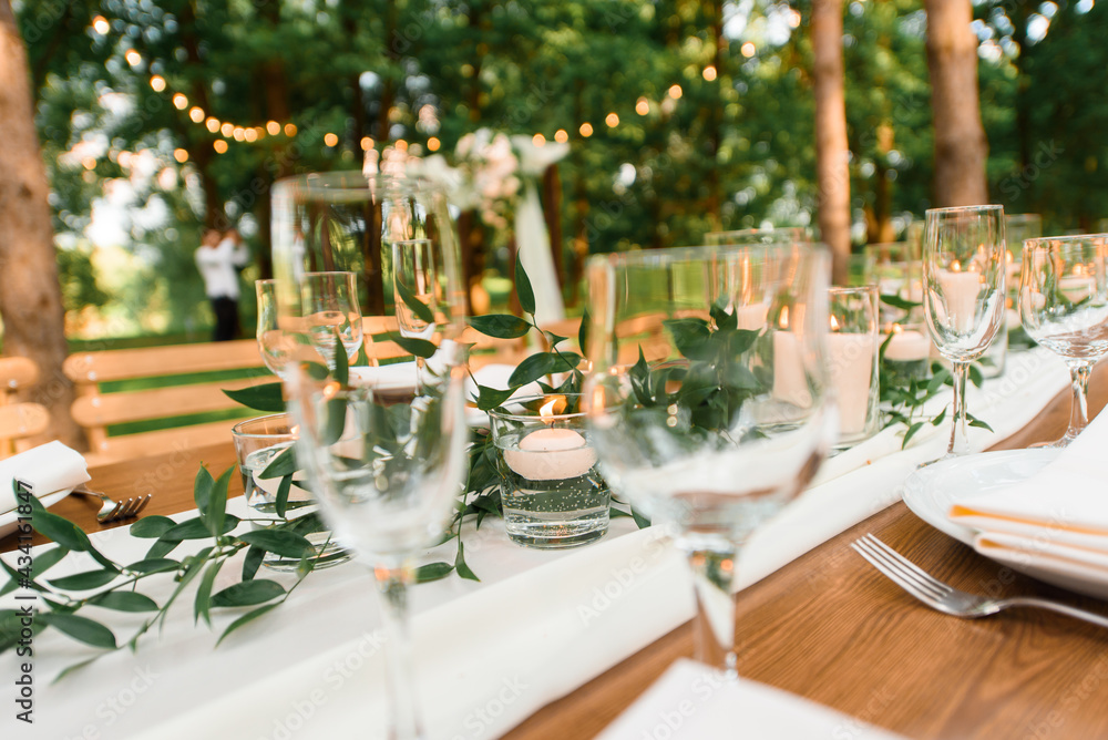setting a wedding banquet in the forest. Rustic style. Green branch and candles. Celebrating a wedding