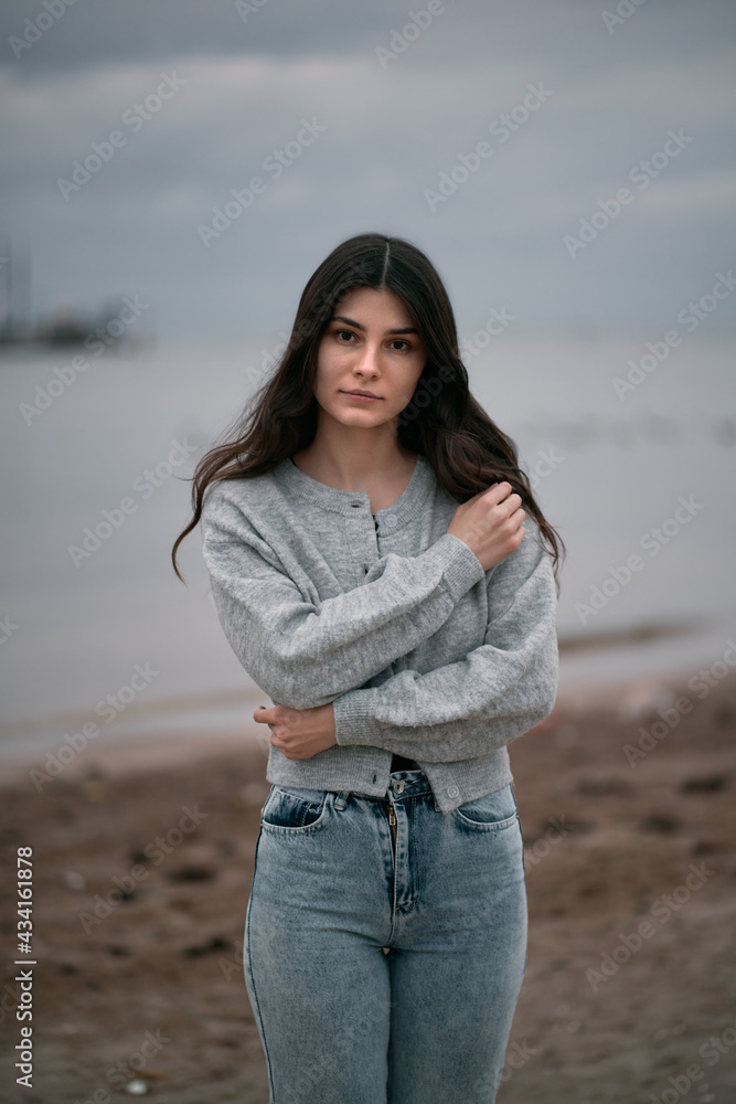 Lonely woman walks on the beach. Clothed brunette walking by seaside on the evening. One girl during spring vacation by the sea. Lonely woman walks on the beach. Clothed brunette walking by seaside on the evening. One girl during spring vacation by the sea.