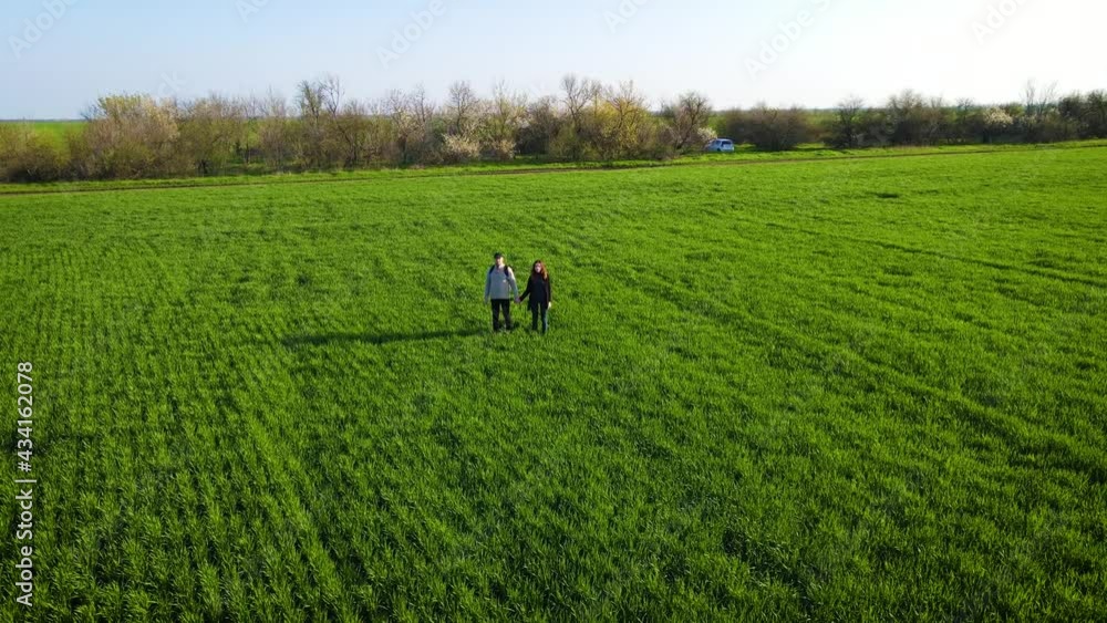 Caucasian woman and man standing in field and talking about harvest. Couple of farmers examining green plants of wheat in sunlight. Active healthy lifestyle and traveling concept Caucasian woman and man standing in field and talking about harvest. Couple of farmers examining green plants of wheat in sunlight. Active healthy lifestyle and traveling concept