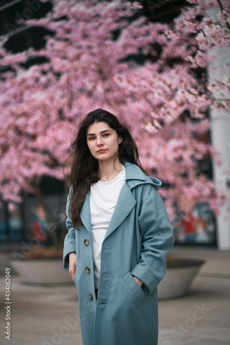 Portrait of young woman with dark long hair. Concept of successful women in business. Spring time with cherry blossoms in downtown of Gdansk, Poland. © AlexGo