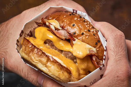 Male's hands holding a delicious double cheeseburger