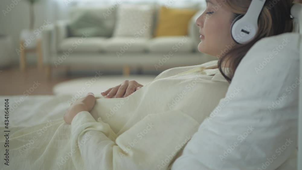 Pregnant woman concept of 4k Resolution. Asian girls are lying listening to music in their bedrooms. Pregnant woman concept of 4k Resolution. Asian girls are lying listening to music in their bedrooms.