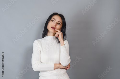 Pretty woman in a white sweater looks at the camera. Portrait of a successful businesswoman