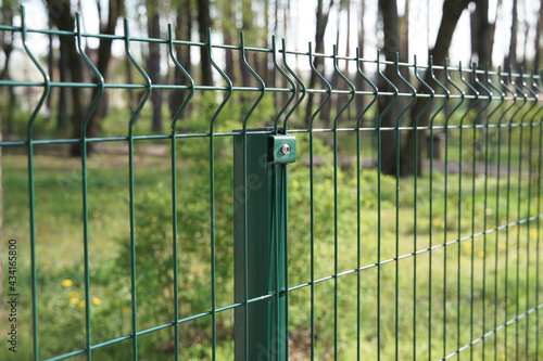 Steel grating fence made with wire on garden background. Sectional fencing installation