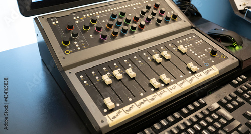 Modern audio mixer with button control panel against computer keyboard on table in sound studio photo
