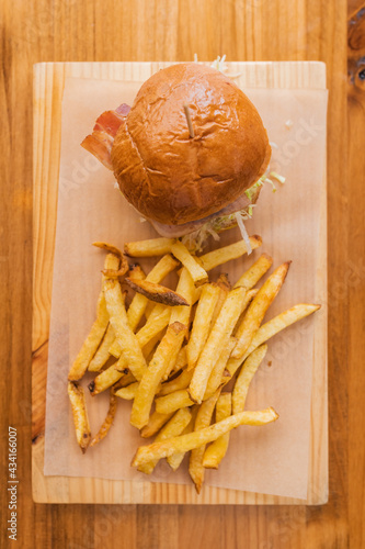 Top view of delicious fresh hamburger and crispy French fries served on wooden board in modern fast food restaurant photo