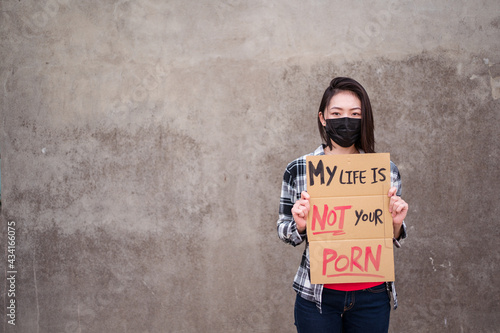 Ethnic female in protective mask standing with My Life Is Not Your Porn carton poster during protect against sexual harassment and assault photo