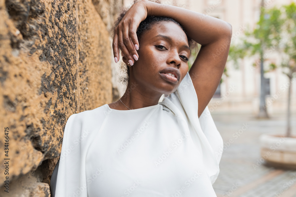 Portrait of attractive African American female standing in historic city district on warm spring day and looking away Portrait of attractive African American female standing in historic city district on warm spring day and looking away