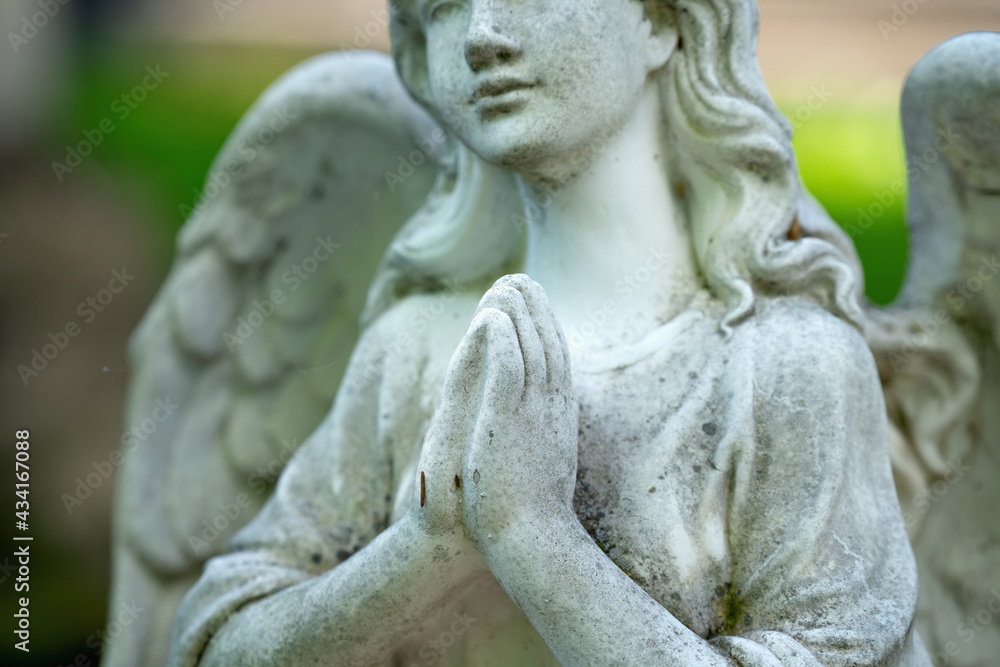 Tender beautiful angel praying. Fragment of an  ancient statue. Selective focus on hands.