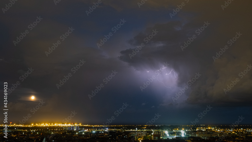 Aerial shot of a thunderstorm over a cityscape at night