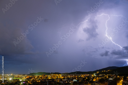 Aerial shot of a thunderstorm over a cityscape at night