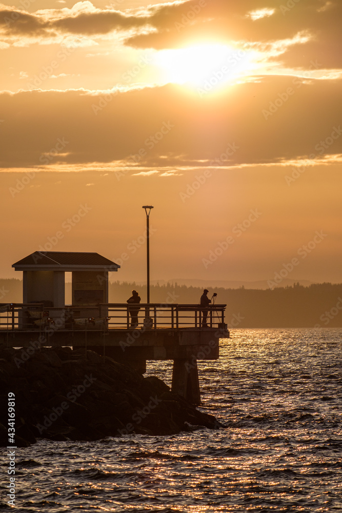 A silhouette of a ferry and a fishing pier at sunset