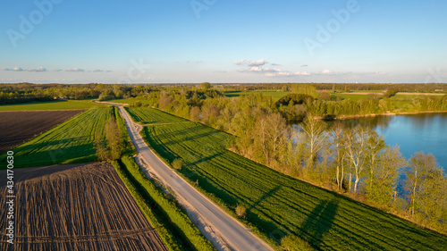 Aerial view with a drone of a spring wavy agricultural countryside landscape with plowed and unplowed fields and trees in the blue evening sky. High quality photo