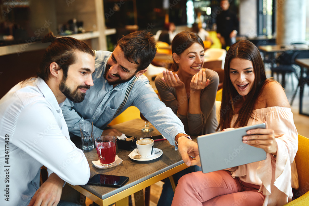 Obraz premium Group of Happy friends having with digital tablet in cafe