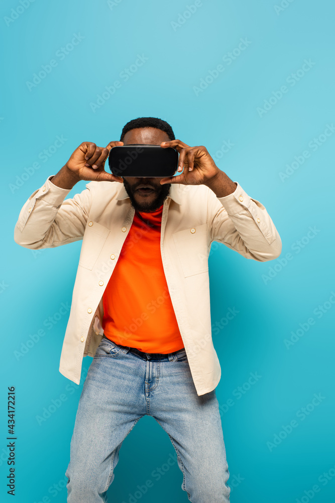 african american man adjusting vr headset on blue background african american man adjusting vr headset on blue background
