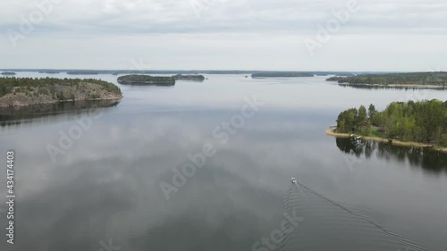 A small motorboat glides over a smooth sea. Flying over the water following the boat. A small islands in the sea. Aerial shooting. photo