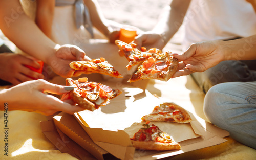 Fototapeta Naklejka Na Ścianę i Meble -  Hands taking slices of pizza close view. Friends eating pizza at the beach. Fast food concept. Beach holiday and summer vacation concept.