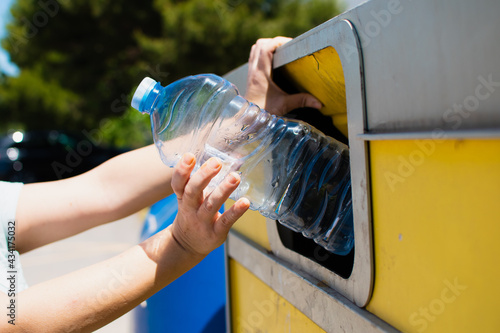 Wallpaper Mural caucasian woman's hand holding a plastic bottle just before dropping it into a yellow recycling garbage can Torontodigital.ca