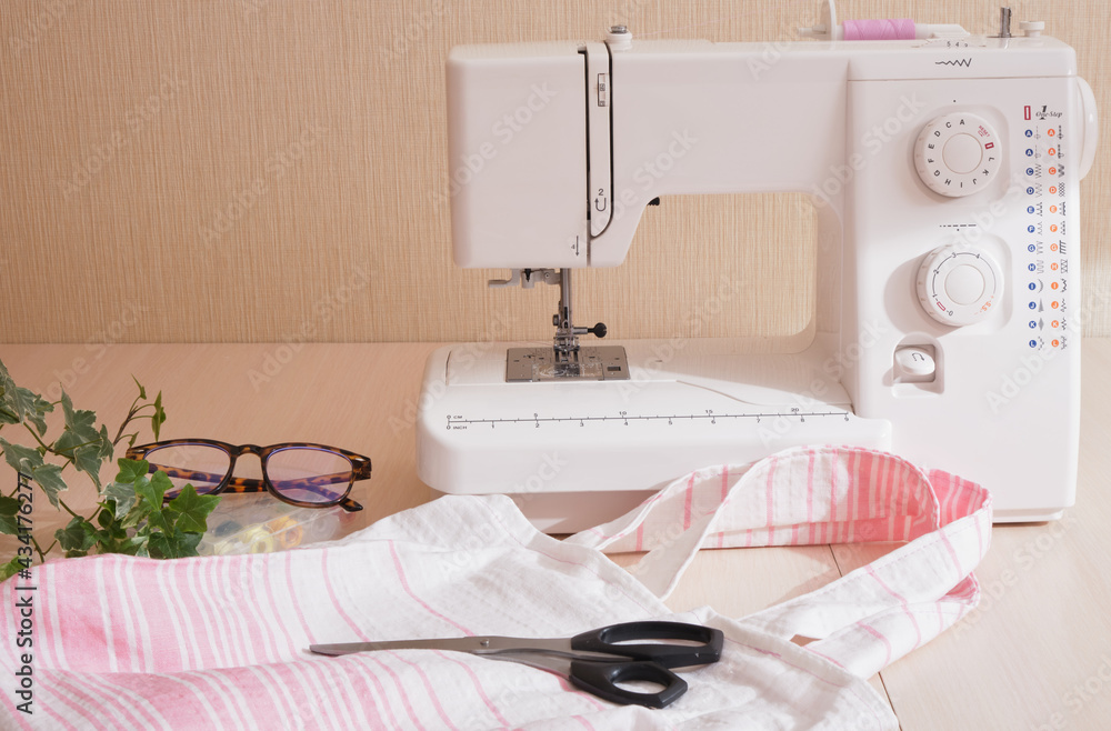 eco shopping bag made of cotton fabric, sewing machine, scissors, glasses and spools of thread on the table, copy space