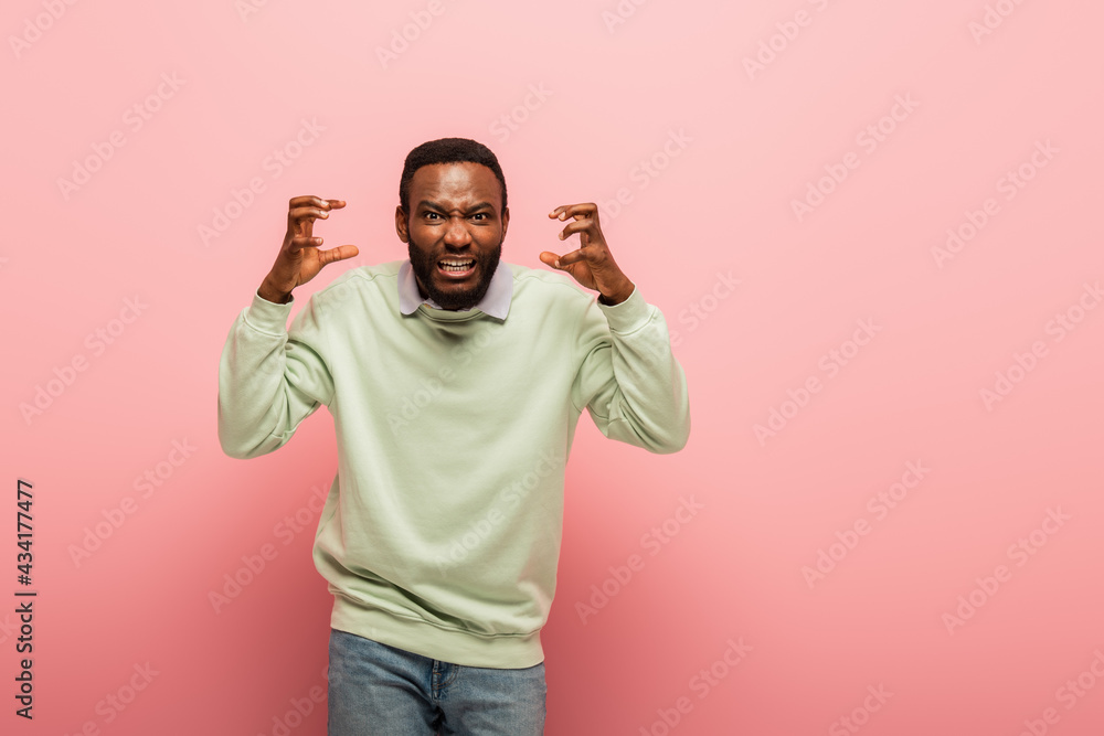 Aggressive african american man looking at camera on pink background Aggressive african american man looking at camera on pink background