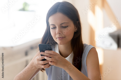 Millennial Caucasian female look at cellphone screen text message online on modern device. Young teenager use smartphone shopping on internet or talk on video webcam call. Technology concept.