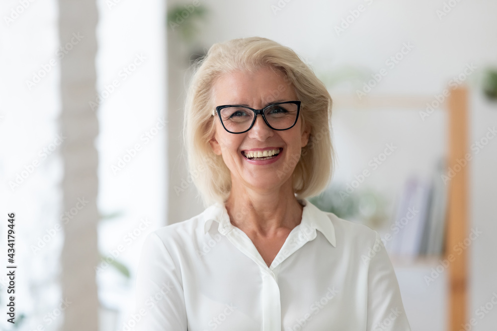 Headshot portrait of smiling senior Caucasian businesswoman in glasses pose in office on working day. Close up profile picture of happy middle-aged female employee or CEO show success at workplace. Headshot portrait of smiling senior Caucasian businesswoman in glasses pose in office on working day. Close up profile picture of happy middle-aged female employee or CEO show success at workplace.