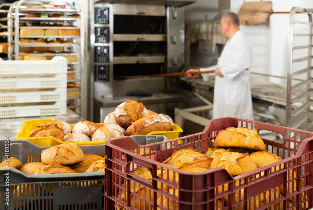 Interior of small bakeshop with box full of freshly baked bread. Breadmaking industry concept..