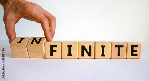 Finite or infinite symbol. Businessman turns wooden cubes and changes the word 'finite' to 'infinite'. Beautiful white table, white background. Business, finite or infinite concept. Copy space. photo