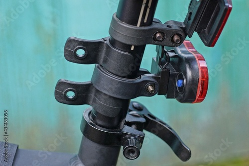 plastic clamps with a warning light and reflector on a black metal tube of the bicycle frame on a green background