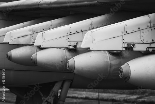 Part of the wing of a jet plane with intimidating missiles. Black and white photo of military equipment.