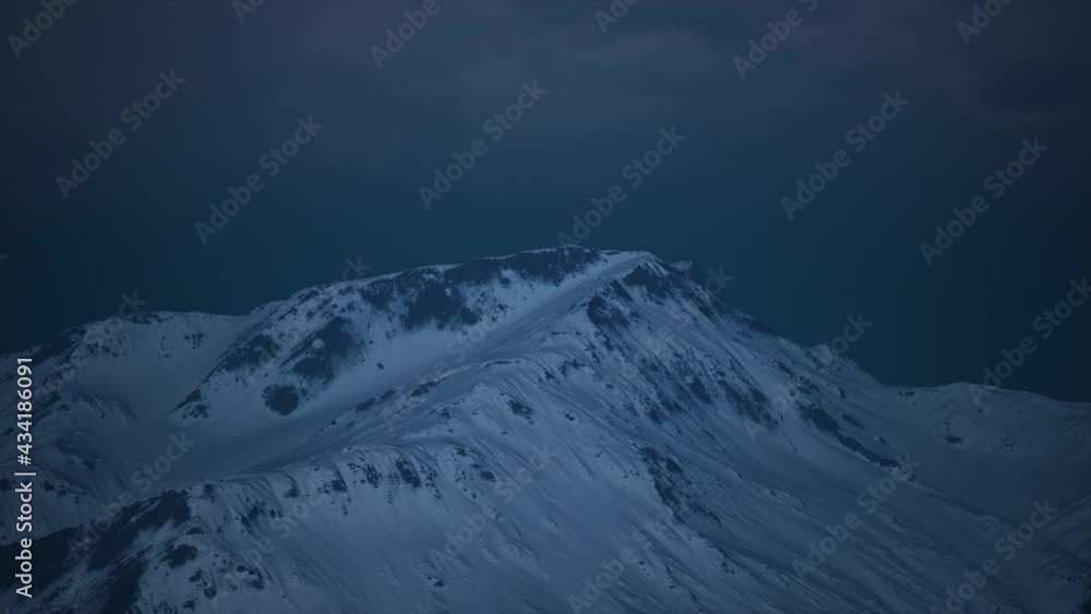 Dramatic dark rocky mountain with patches of snow in storm Dramatic dark rocky mountain with patches of snow in storm