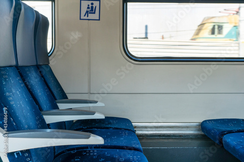 Side view of blue armchairs in empty train in row of three, no people in wagon, comfortable way of transportation, travelling concept