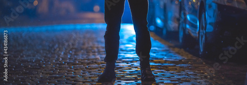 The man stand on the wet road. Evening night time. Telephoto lens shot
