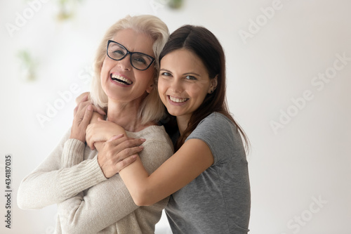 Slika na platnu Family portrait of happy mature old mother and adult teenage daughter hug and cuddle spend weekend time together