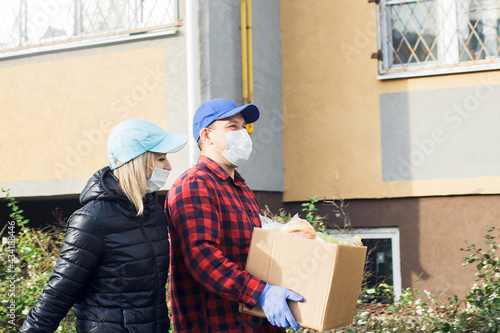 volunteers in protective masks walk down the street with a box of groceries, charity © vilma3000