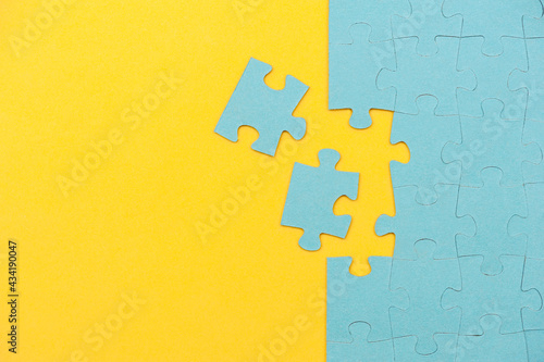 Blue puzzle background with missing piece on yellow background. Top view 