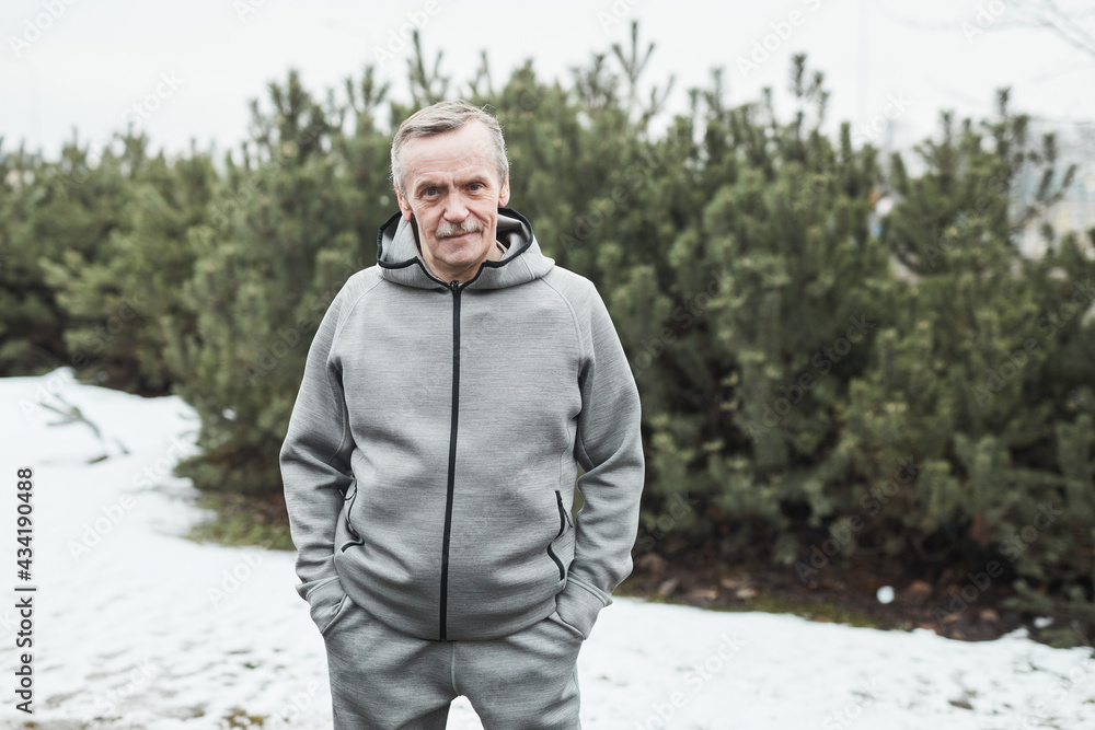 Φωτογραφία Portrait of content confident senior Caucasian jogger in gray sport suit standin