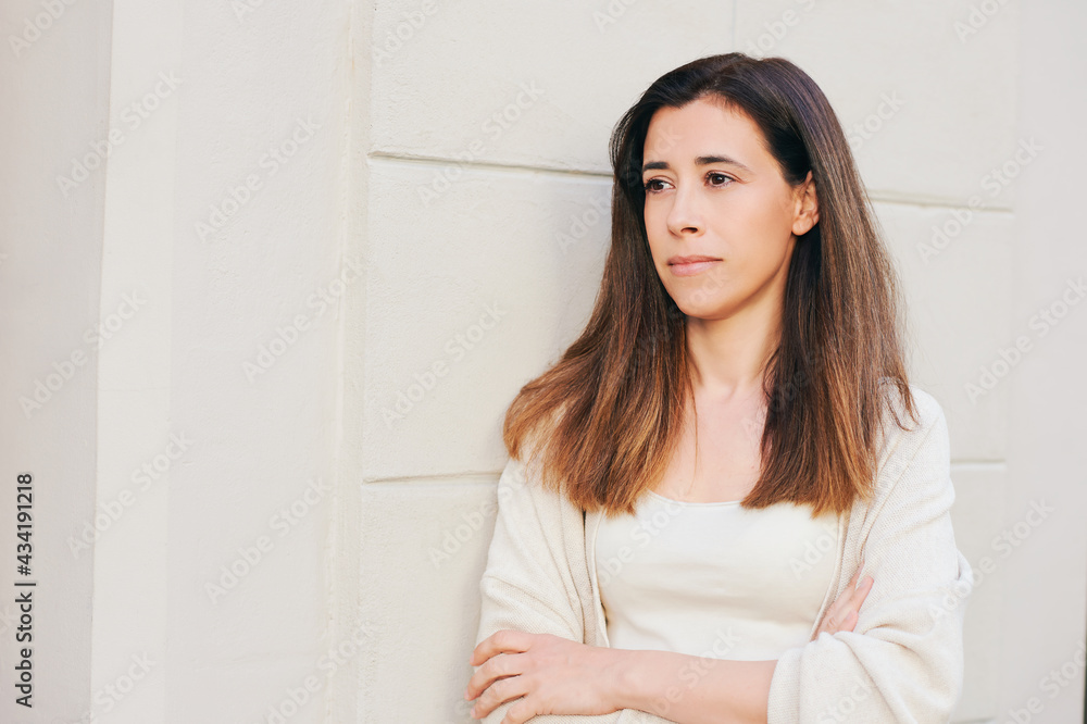 Outdoor portrait of beautiful hispanic woman leaning on the wall, wearing beige clothing Outdoor portrait of beautiful hispanic woman leaning on the wall, wearing beige clothing