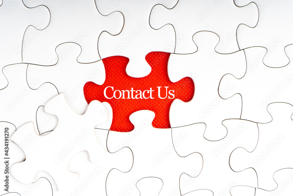 CONTACT US text with jigsaw puzzle on red background. Business and Support Concept CONTACT US text with jigsaw puzzle on red background. Business and Support Concept
