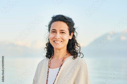 Outdoor portrait of beautiful middle age hispanic woman enjoying nice sunny day by the mountain lake