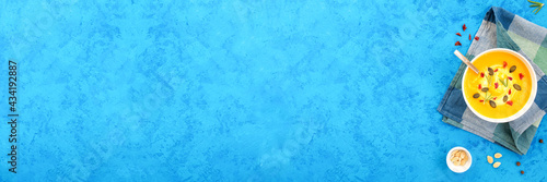 Pumpkin soup on blue concrete background, banner, top view, copy space.