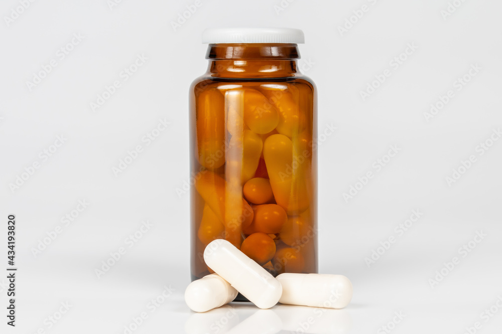 brown glass bottle with white capsules on white background with reflection