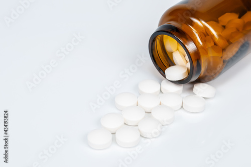 brown glass bottle with white pills on white background