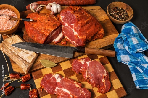 Meat, Pork neck in marinade and on a chopping boardon. Raw steak meat pork neck on chopping board with chili. Raw meat for grilling. Black background. photo