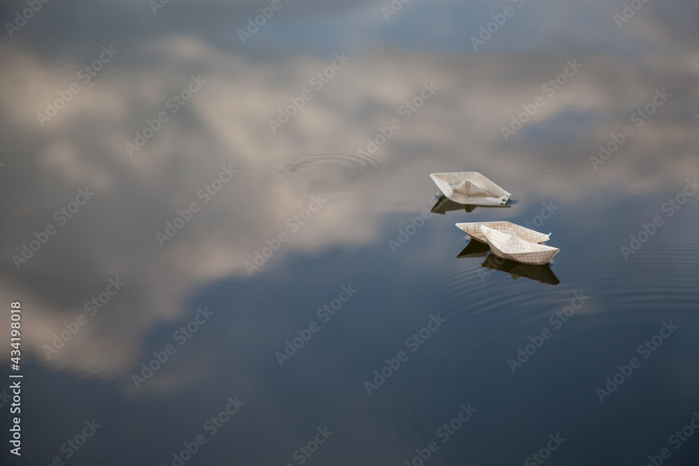small paper boats in water with sky reflection small paper boats in water with sky reflection