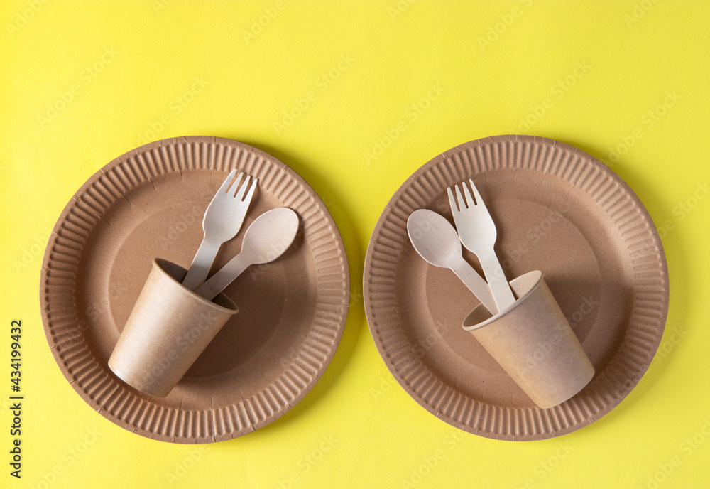 Two sets disposable biodegradable tableware of craft paper and wood - plates, forks, spoons, glasses. Zero Waste. View from the top. Flat lay Two sets disposable biodegradable tableware of craft paper and wood - plates, forks, spoons, glasses. Zero Waste. View from the top. Flat lay