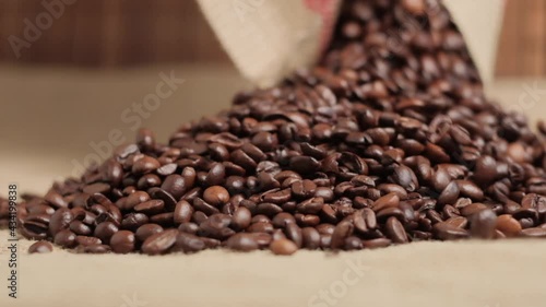Close-up of roasted coffee beans spilling out of a burlap sack. An ingredient for making coffee. Environmental materials. Natural coffee. 4k video.